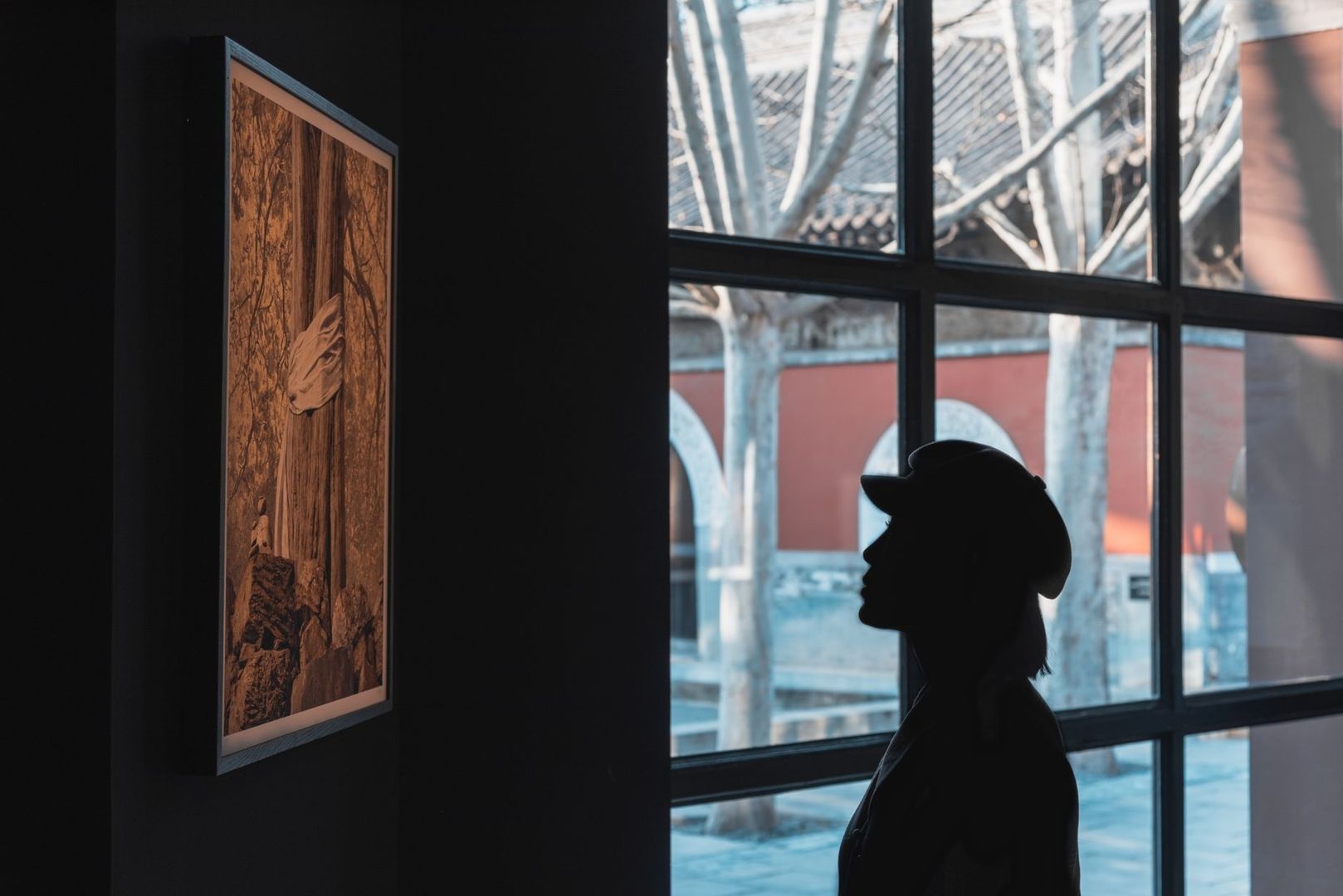 Silhouette vor gerahmtem Kunstwerk hinter einer großen Fensterscheibe