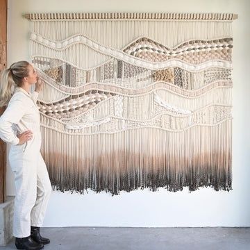 Großes gewebtes Wandkunstwerk in Creme- und Grautönen neben einer Person